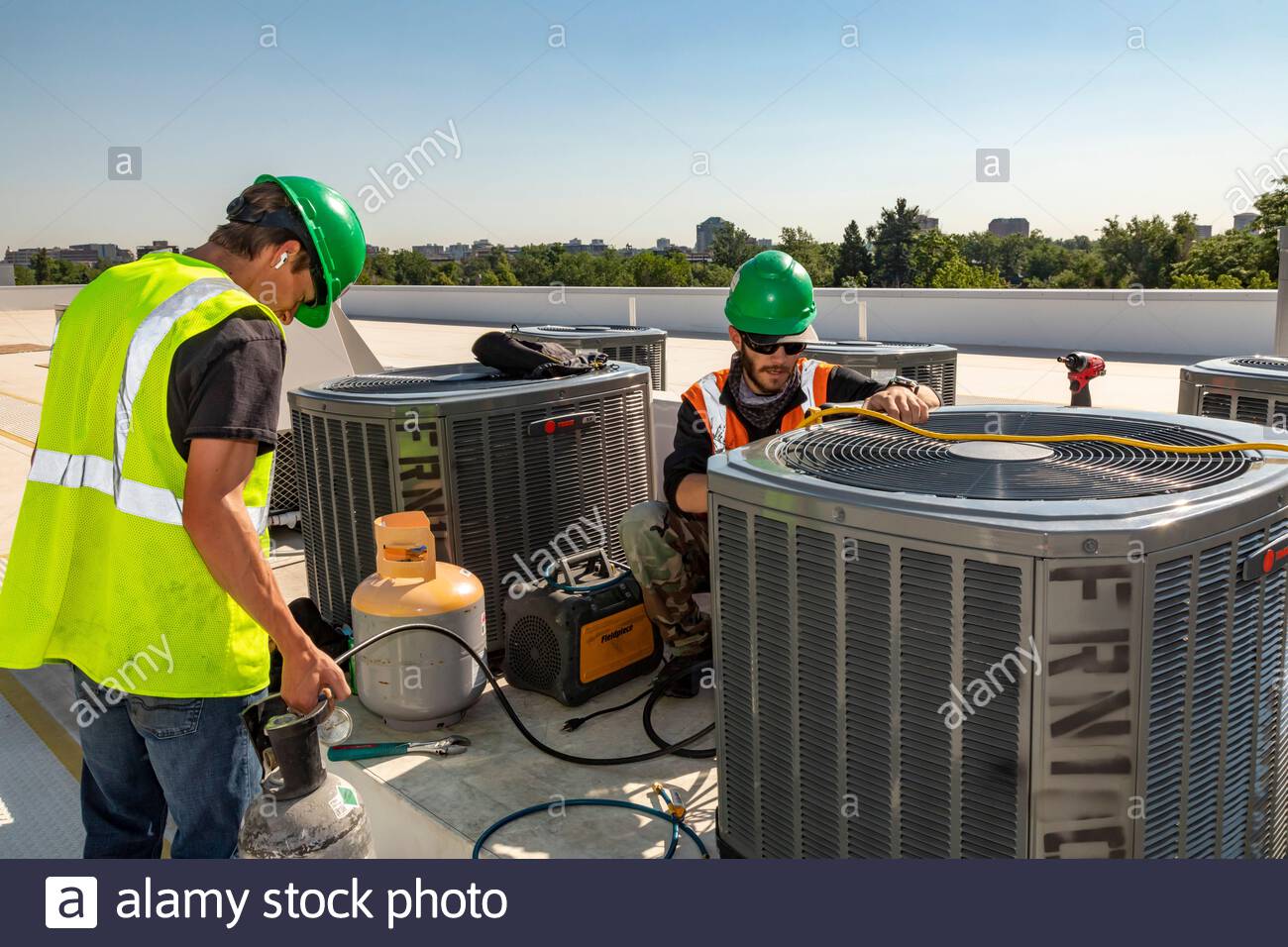 denver-colorado-los-tecnicos-trabajan-en-el-sistema-de-aire-acondicionado-en-el-techo-de-un-edificio-de-vivienda-asequible-en-construccion-2ca7hfm